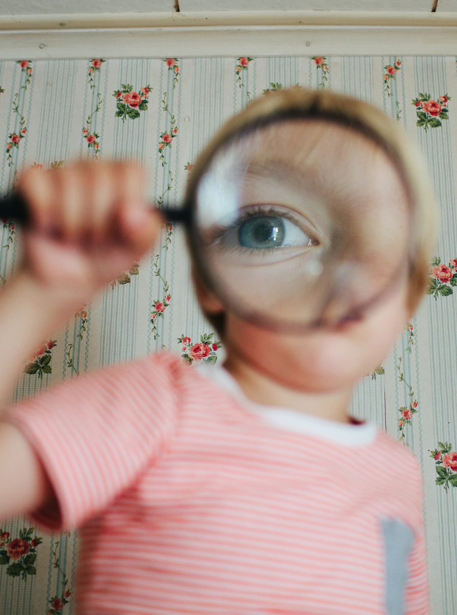 A child looks through a magnifying glass.
