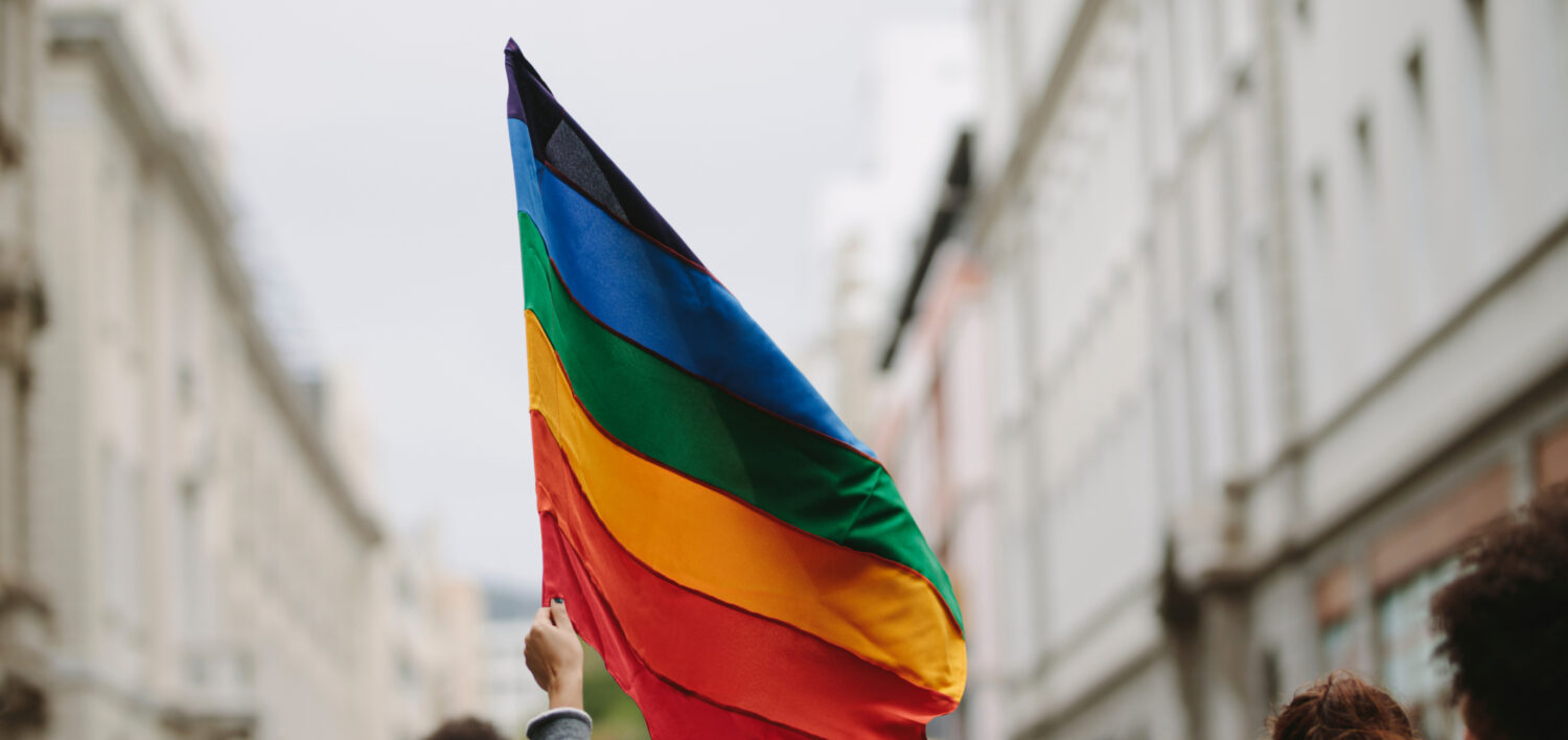 A pride flag waving in a city.